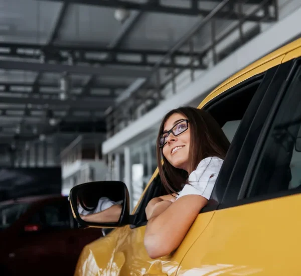 smiling-woman-inside-a-yellow-car-looking-up-2026-01-09-00-39-43-utc-rof2zgkau290zfo7ky440f7091eygqaafe7anfdsak